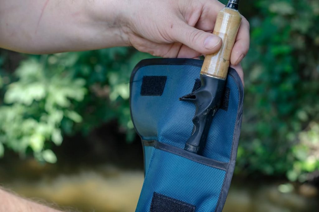 Hand taking a casting rod out of travel bag.