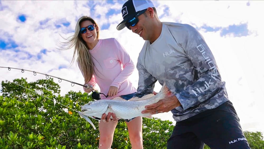 Man and woman in fishing clothing while holding a fish