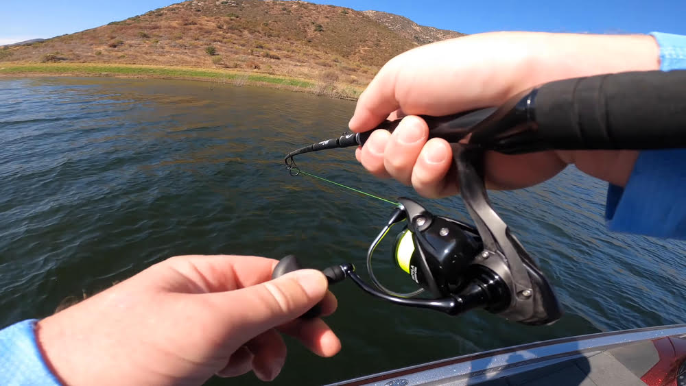 Casting a Daiwa Tatula LT Spinning Reel, with a hand holding a bottle of water.