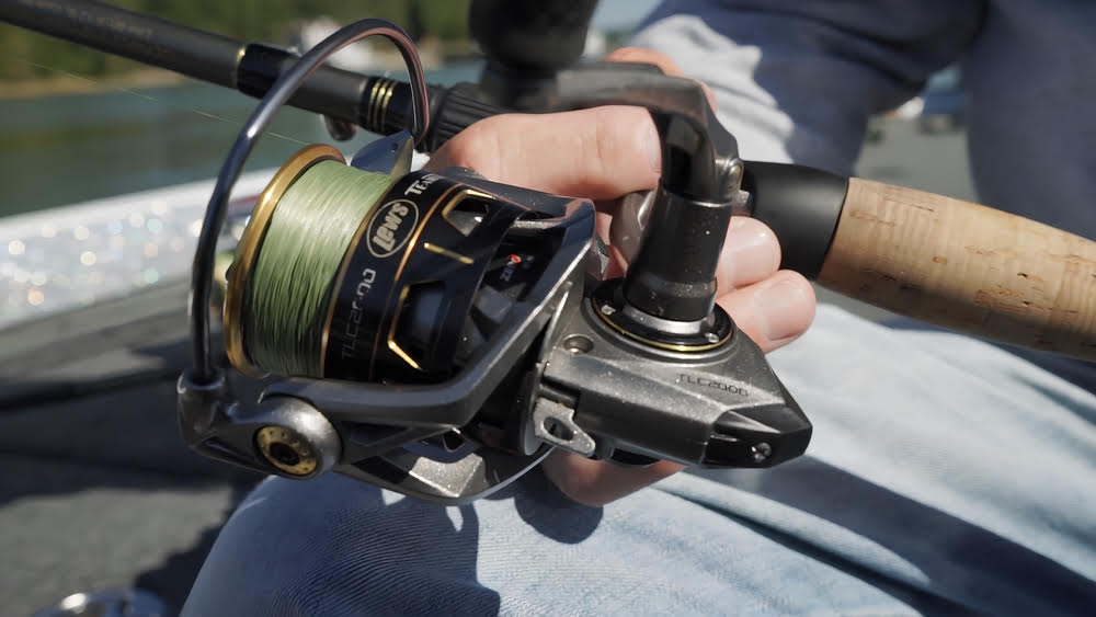 Tight shot of the Lews Custom Pro Spinning Reel in a person's hand.