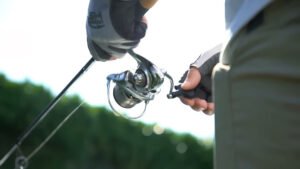 Aperson admiring the Daiwa Procyon MQ LT Spinning Reel against a mirror backdrop.