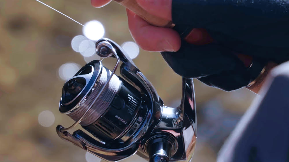 Aperson holding the Stella FK Spinning Reel, on a blue motorcycle.