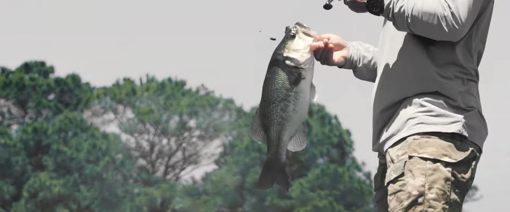 A man holding a bass caught during cold front fishing in spring