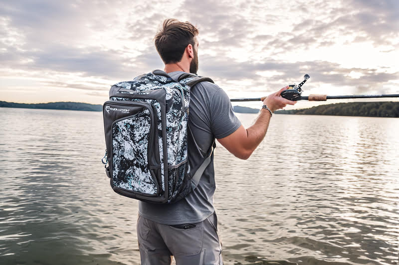 A man fishing on a boat with the Evolution Outdoor Large Mouth Double Decker Backpack