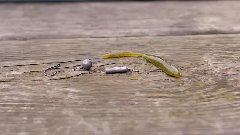 A pair of fishing hooks, including a fish hook, on a wooden surface